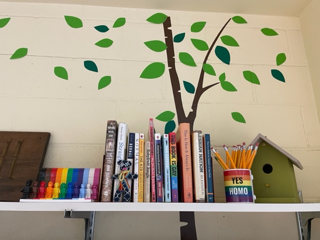 A shelf of LGBTQ+-focused books and decorations in Mary Wiltenburgs Upper School English classroom.