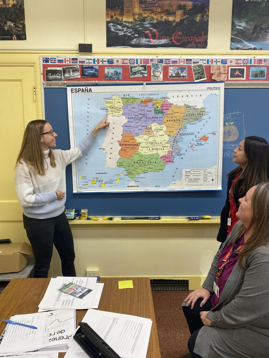 Spanish teacher Marta Reinaldo points to a map of Spain, as colleague Lee Roby and a student look on.