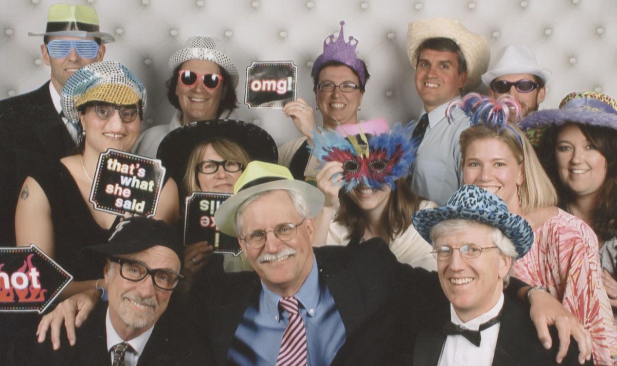 Koniezhny (holding upside down sign) and other teachers and administrators dress up and pose in a photo booth at Prom 2013.