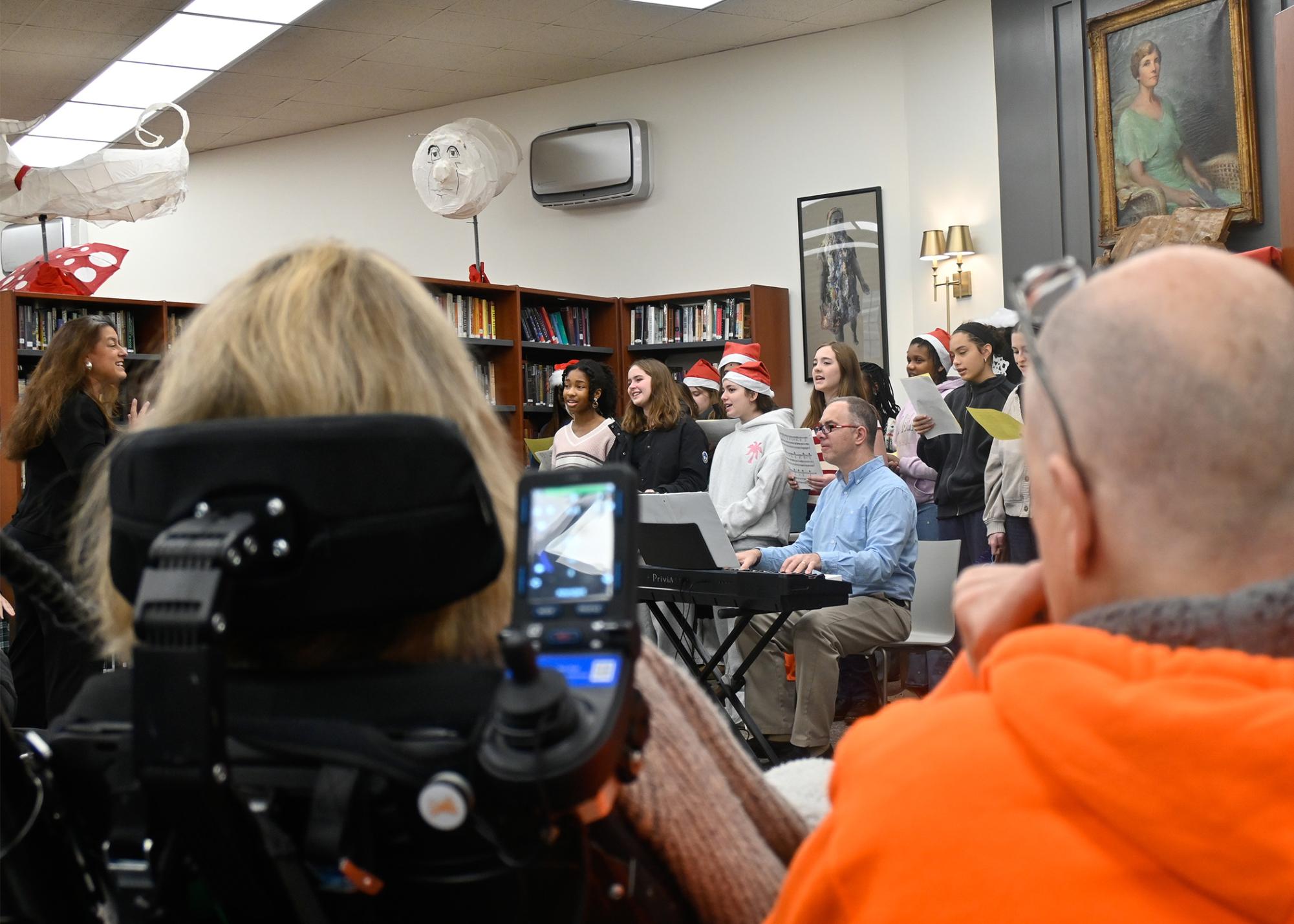 Koniezhny and partner Danny Mydlack watch Zara Davis '30 (left) and the middle school chamber choir perform a special holiday concert in the Library in December 2025, complete with French songs and a sing-along.