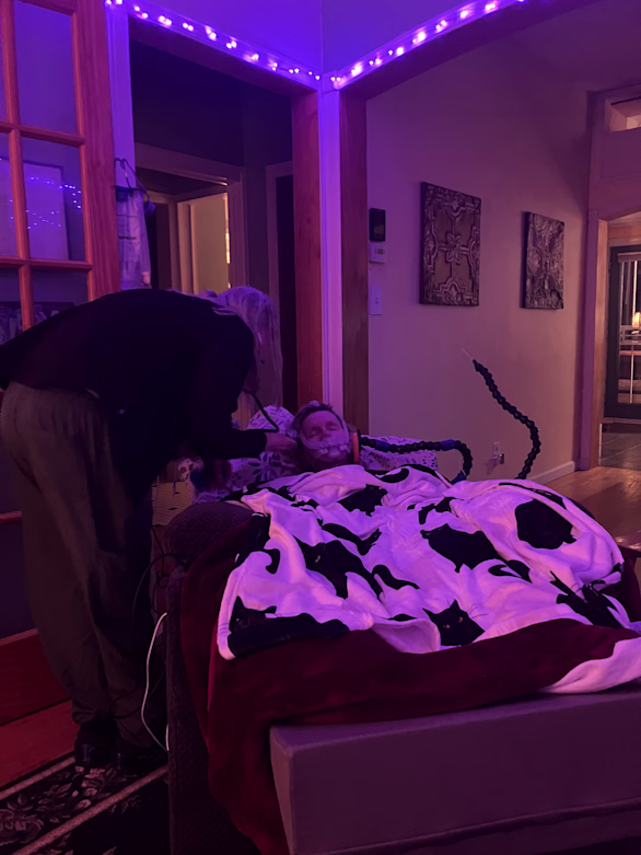 On the night of February 28th, a hospice nurse gives medicine to ease Koniezhny's suffering. Mydlack has lit the room in a soothing purple. In a CaringBridge update, he writes that their cats have been head-butting Koniezhny for attention. "I catch my mind running off suddenly, circling wide to take in everything," he writes. "In the dark, Christine is flying around me in her unspeakable beauty and hilarity and we are driving to work, we are bicycling in the woods, we are pulling a roast duck from the oven. The imagination just pulls out all the stops."
